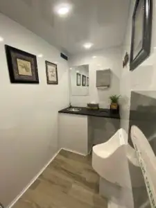 A dark counter, framed pictures and a urinal inside a High Throne trailer