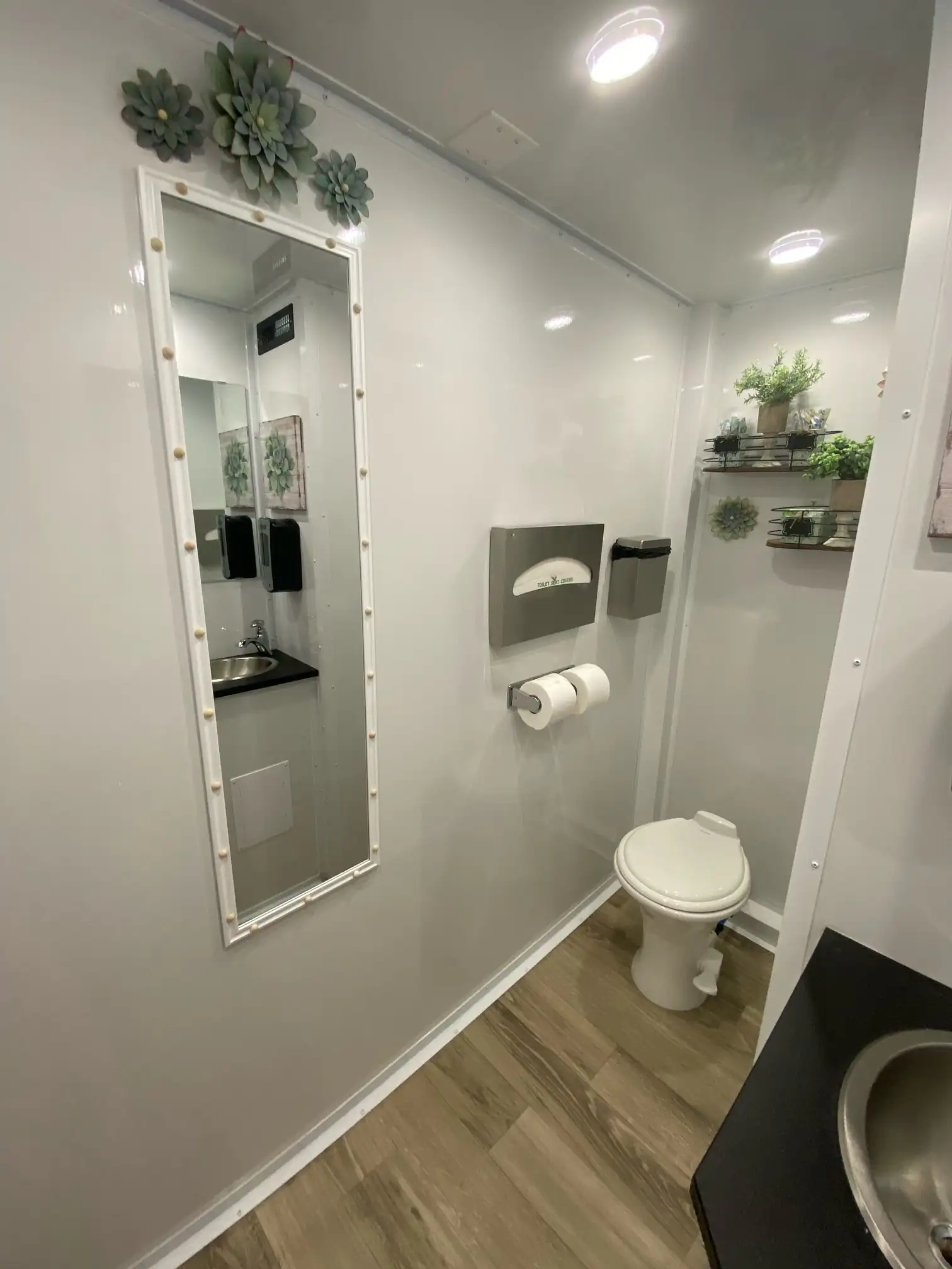 A porcelain toilet and a mirror framed with succulents inside the R300