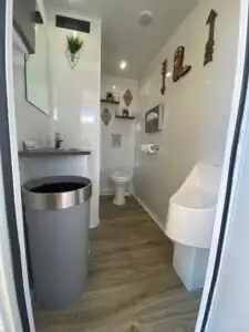 A steel trash can, sink and urinal inside a High Throne trailer