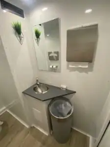A corner sink, mirror and paper towel dispenser inside a High Throne trailer