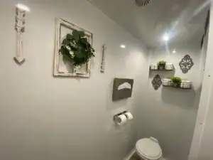 A toilet below a wreath-framed mirror inside a High Throne trailer
